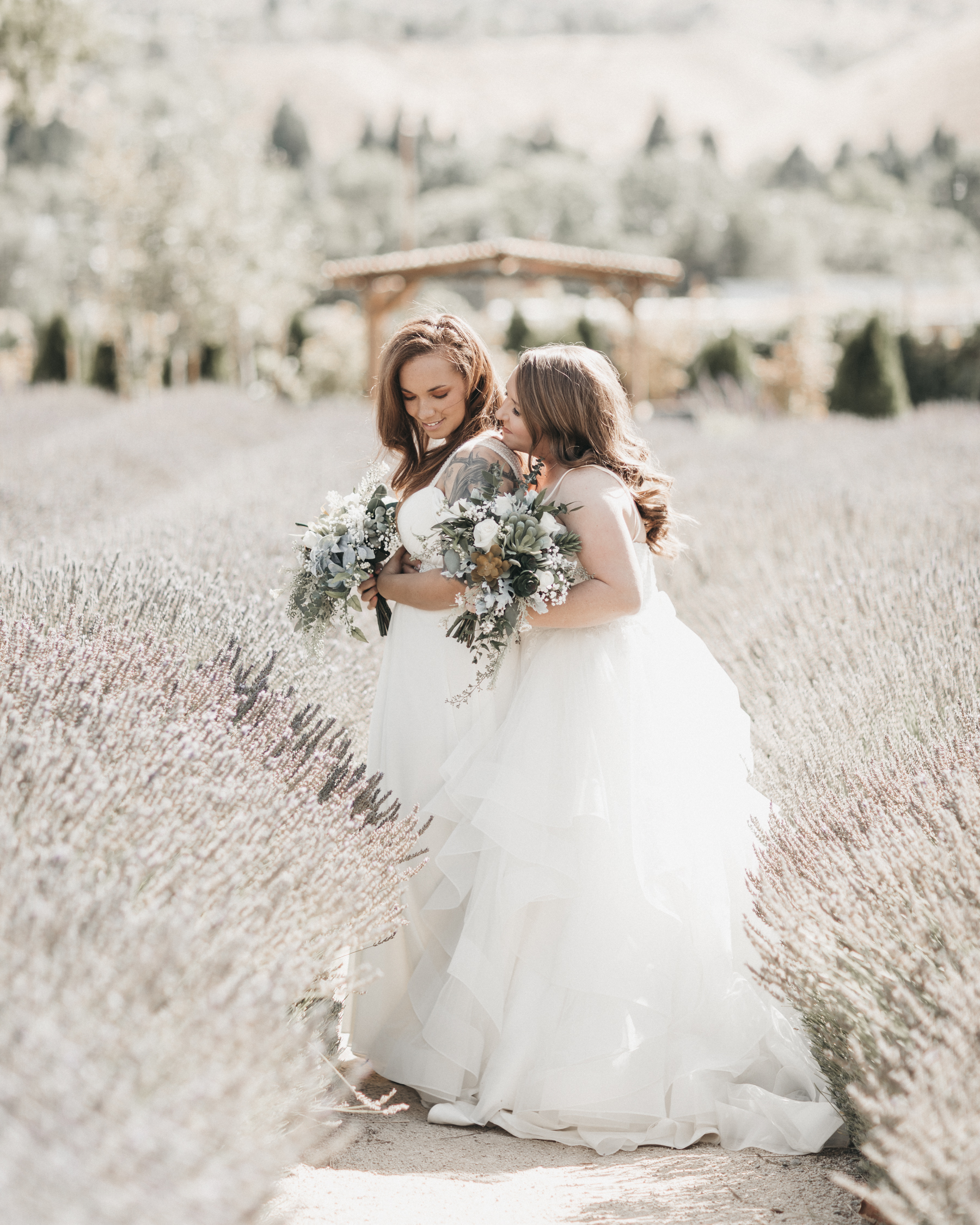 Wedding photography of two brides at Lavender Ridge in Reno, Nevada. Alina and Brittany are both wearing white wedding dresses and have bouquets made of white roses and succulents.